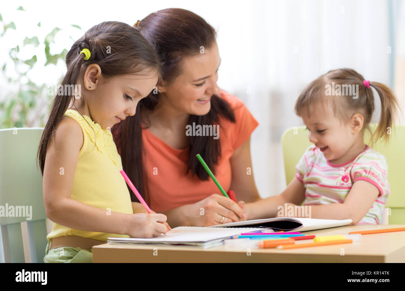 Dei bambini felici con insegnante disegno in aula Foto Stock
