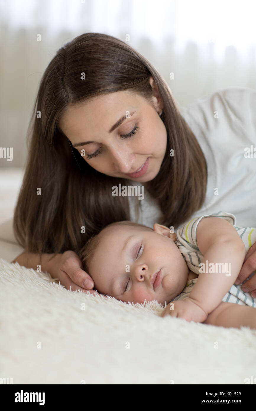 Bella giovane mamma e bambino dorme nel letto di casa Foto Stock