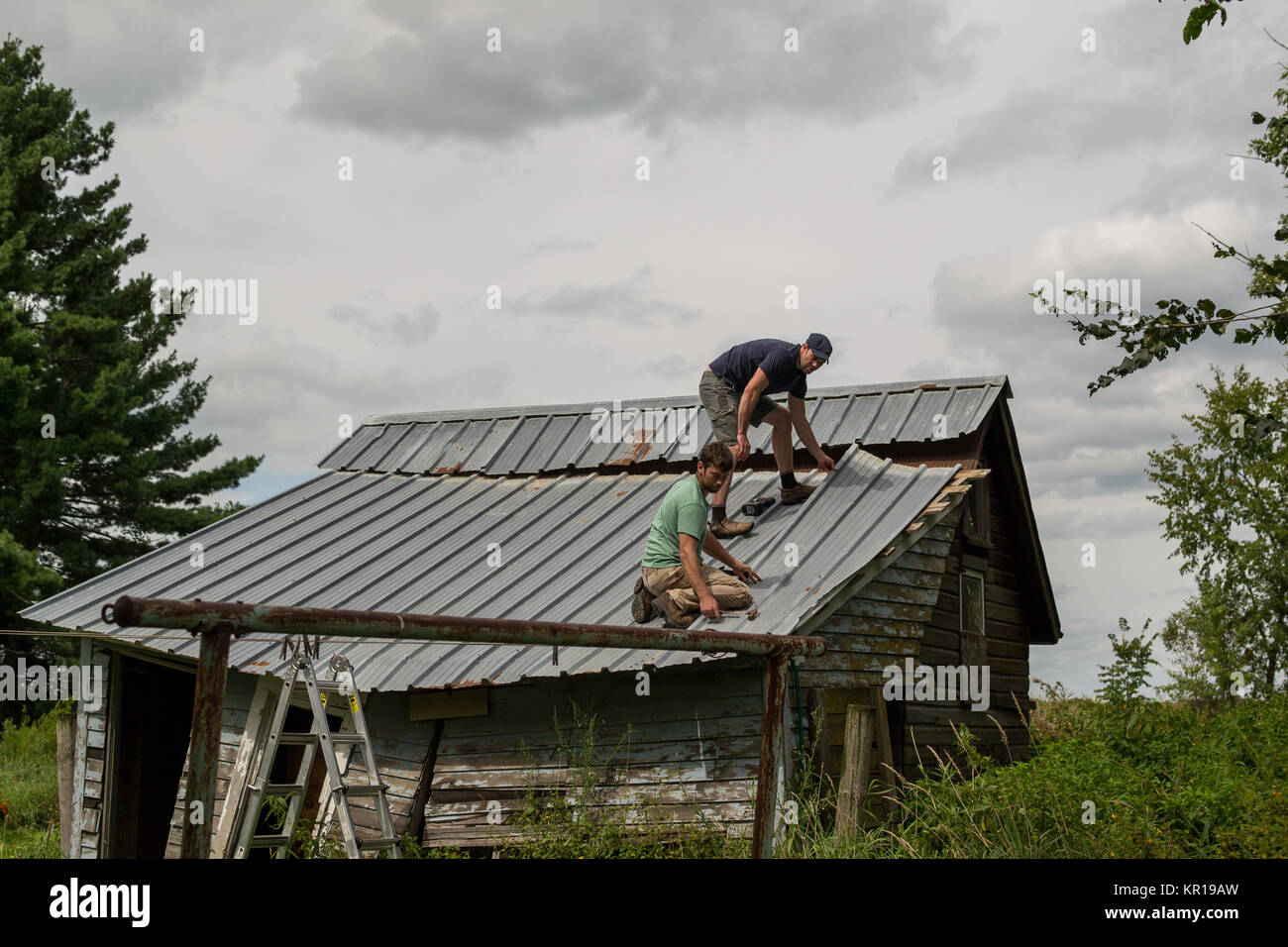 Due uomini al lavoro sul tetto di un vecchio capannone Foto Stock