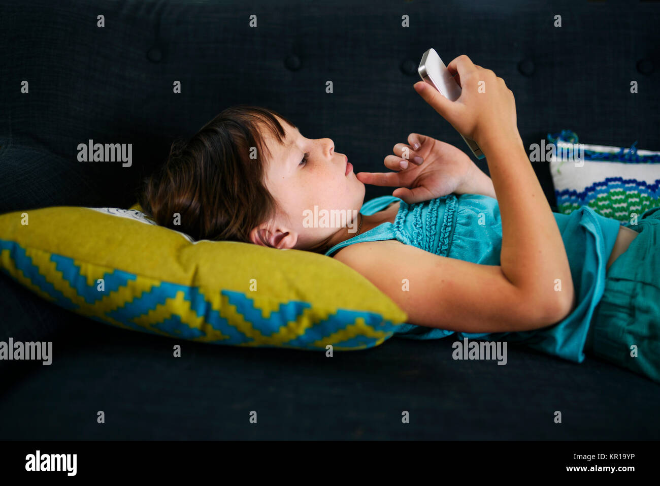 Ragazza distesa sul divano guardando il suo smart phone Foto Stock