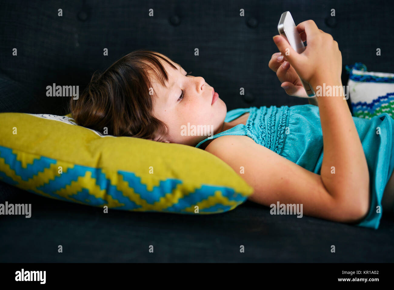 Ragazza distesa sul divano guardando il suo smart phone Foto Stock