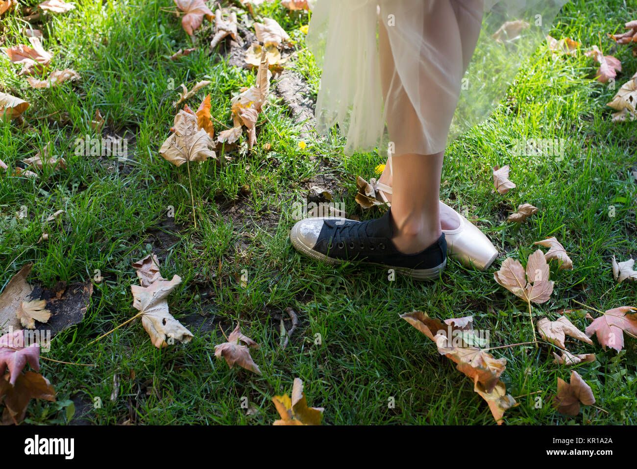 Donna in piedi all'aperto indossare una scarpa di balletto e uno sneaker Foto Stock