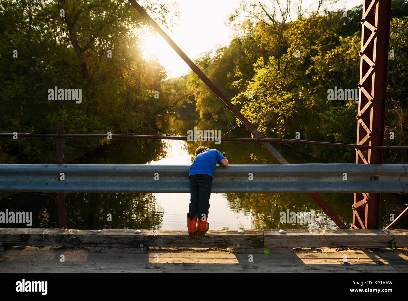 Ragazzo in piedi su un ponte la pesca Foto Stock