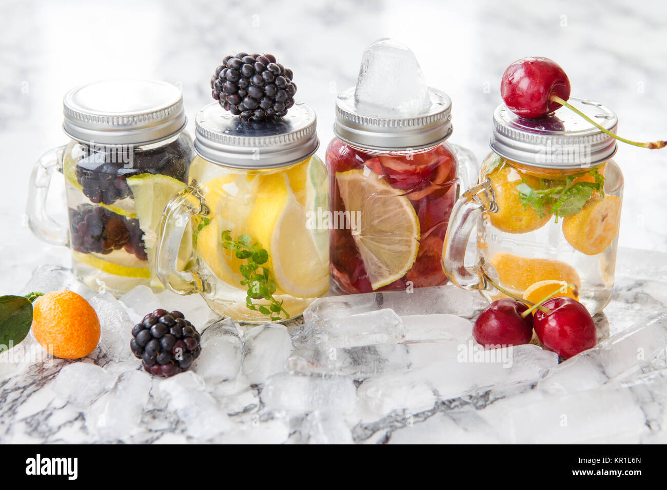 Frisches Wasser mit bunten Fruechten in kleinen Einmachglaesern Foto Stock