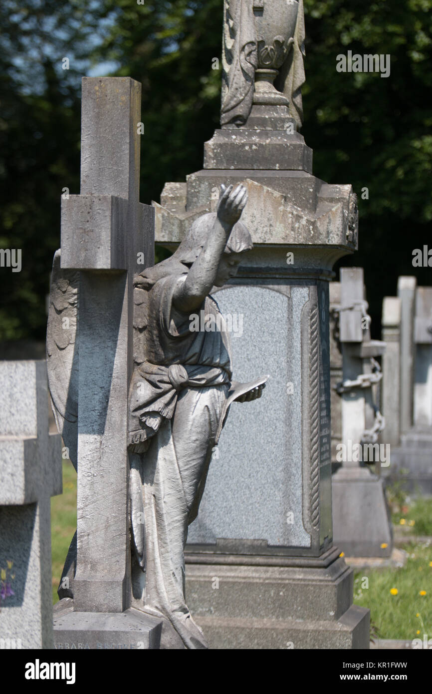 La scena del cimitero con un angelo di pietra con un braccio sollevato che figurano tra gli altri lapide e monumenti. Foto Stock