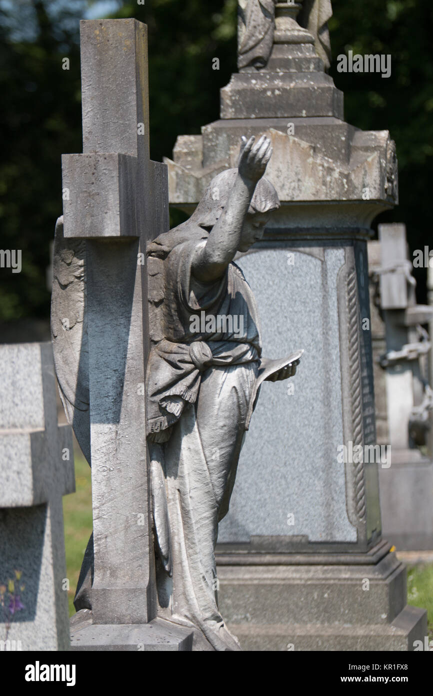 La scena del cimitero con un angelo di pietra con un braccio sollevato che figurano tra gli altri lapide e monumenti. Foto Stock
