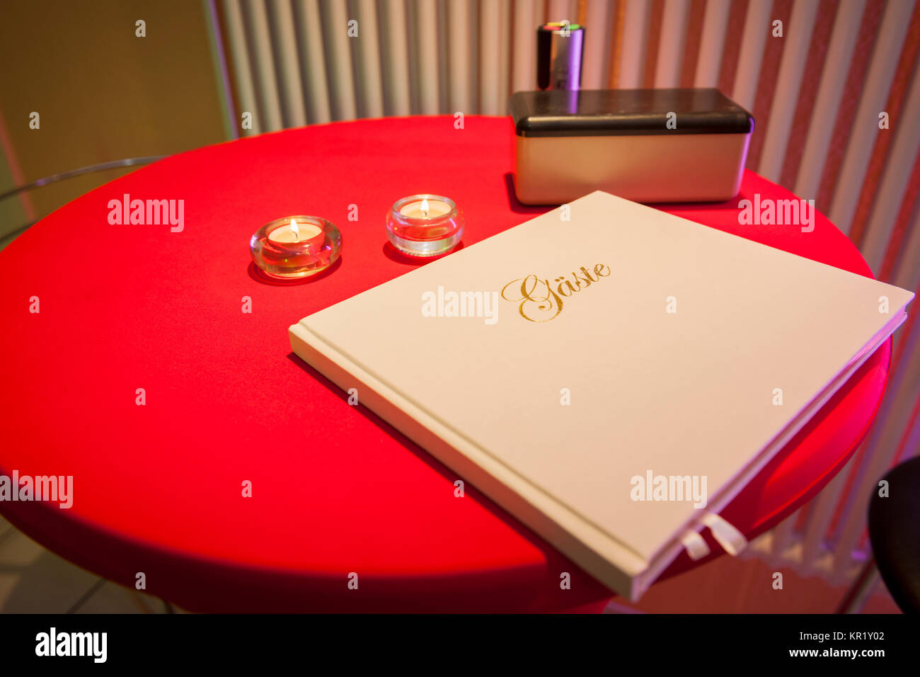 Nahaufnahme eines roten Stehstisches runden mit Gästebuch und Teelicht Foto Stock