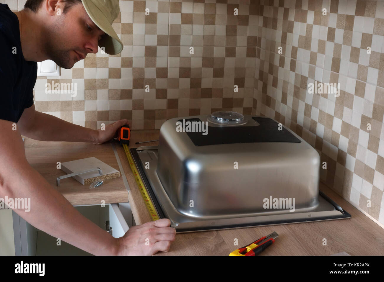 Un lavello da cucina installazione da parte di un maestro in cucina. Foto Stock