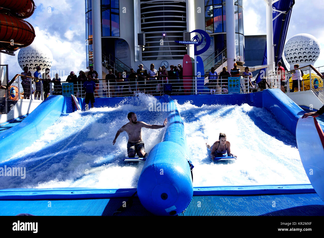 Linea di spettatori Royal Caribbean la libertà dei mari flowridere attività per guardare i passeggeri sfida il rapido fluire acqua su tavole boogie. Foto Stock