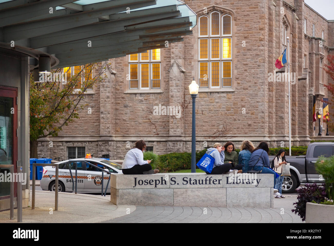 Gli studenti rilassante sul segno per il Giuseppe S. Stauffer biblioteca presso la Queen's University a Kingston a Kingston, Ontario, Canada. Foto Stock