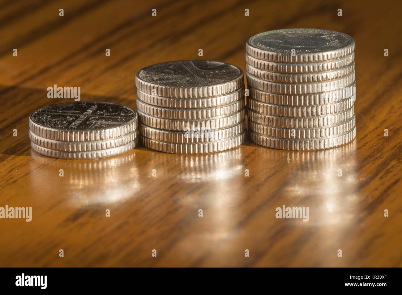 Tre pile di 5 pence monete di diverse dimensioni su un tavolo Foto Stock
