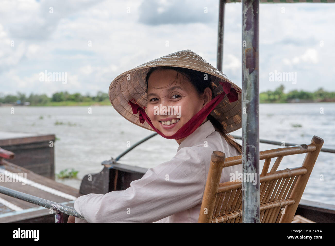 Il vietnamita donna seduta in una barca tradizionale nel delta del Mekong vicino a Vinh Long. Il fiume Mekong è una strada di grande importanza per i trasporti nel sud-est un Foto Stock