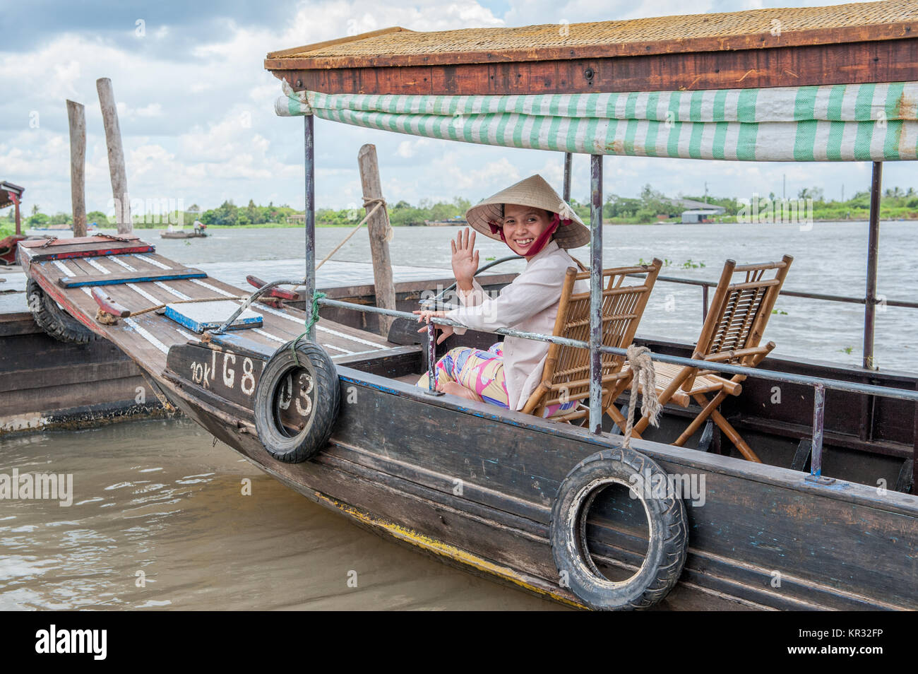 Il vietnamita donna seduta in una barca tradizionale nel delta del Mekong vicino a Vinh Long. Il fiume Mekong è una strada di grande importanza per i trasporti nel sud-est un Foto Stock