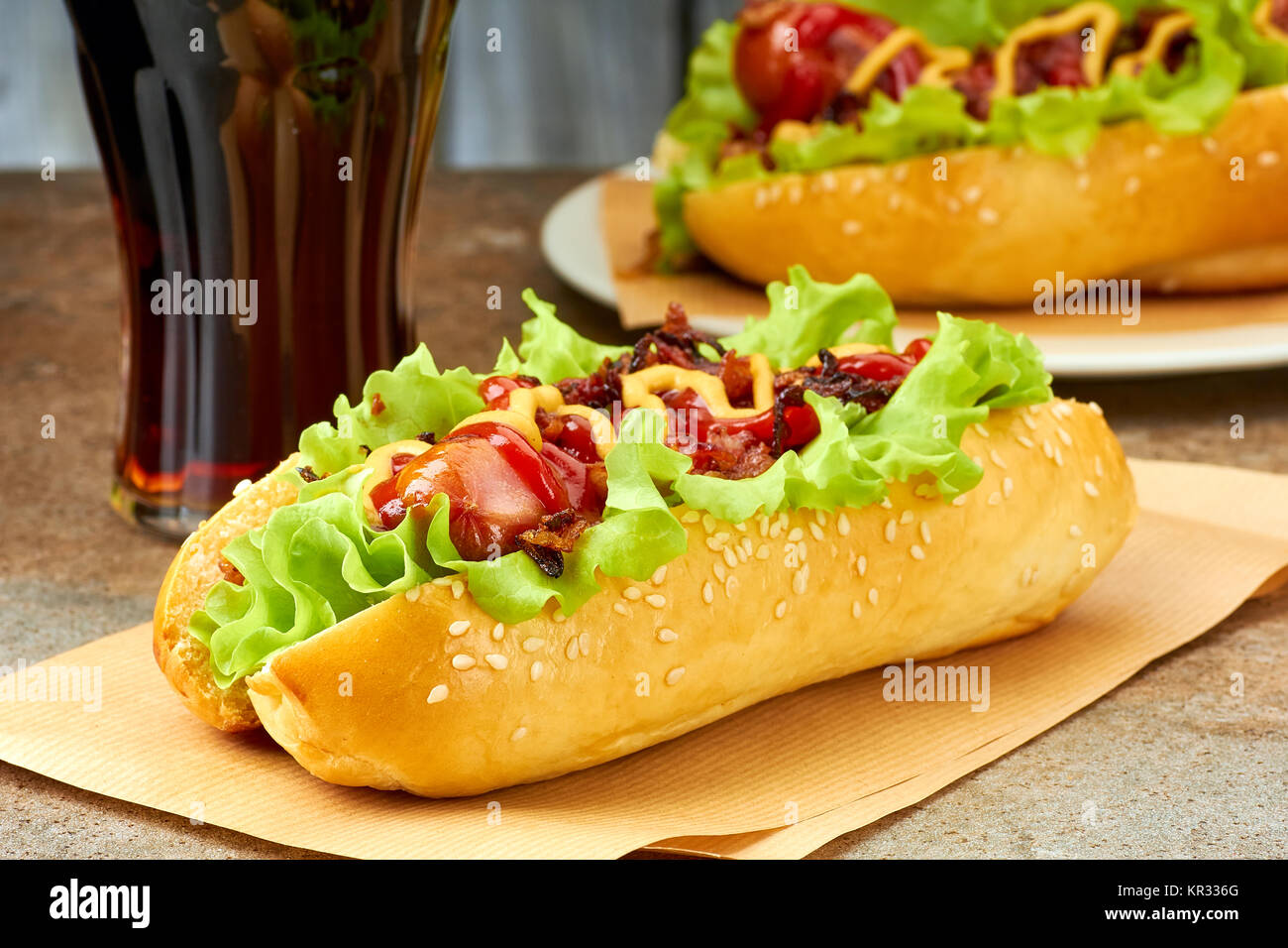 Due hot dogs con condimenti e bicchiere di cola Foto Stock