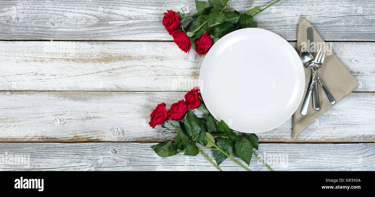 Impostazione di cena con rose rosse sul bianco rustico in legno piatta vista laici per San Valentino vacanza Foto Stock
