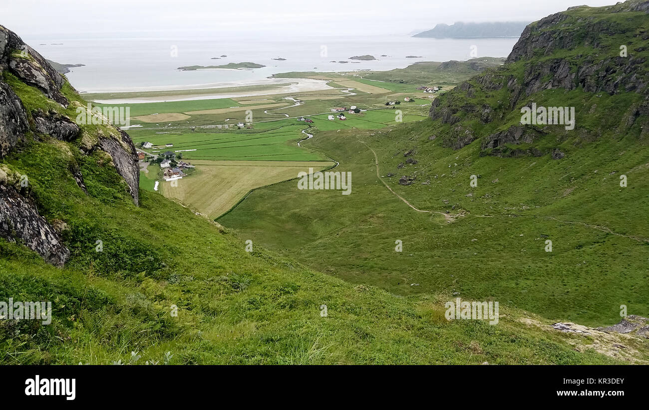 Artico norvegese costa dell'oceano paesaggio con valle verde e piccolo villaggio tra la montagna Foto Stock