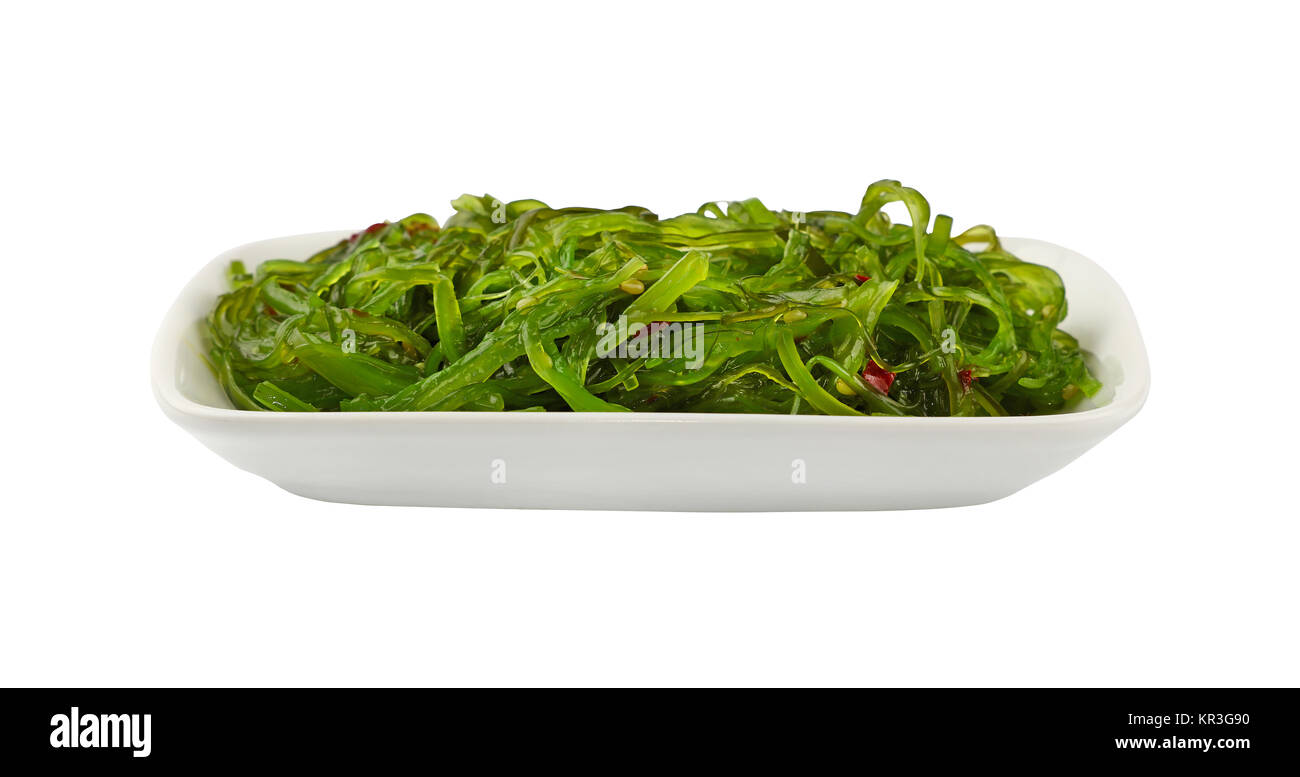 Vicino la porzione di verde alghe wakame salad sulla piastra bianca isolata su sfondo bianco, basso angolo di visione Foto Stock