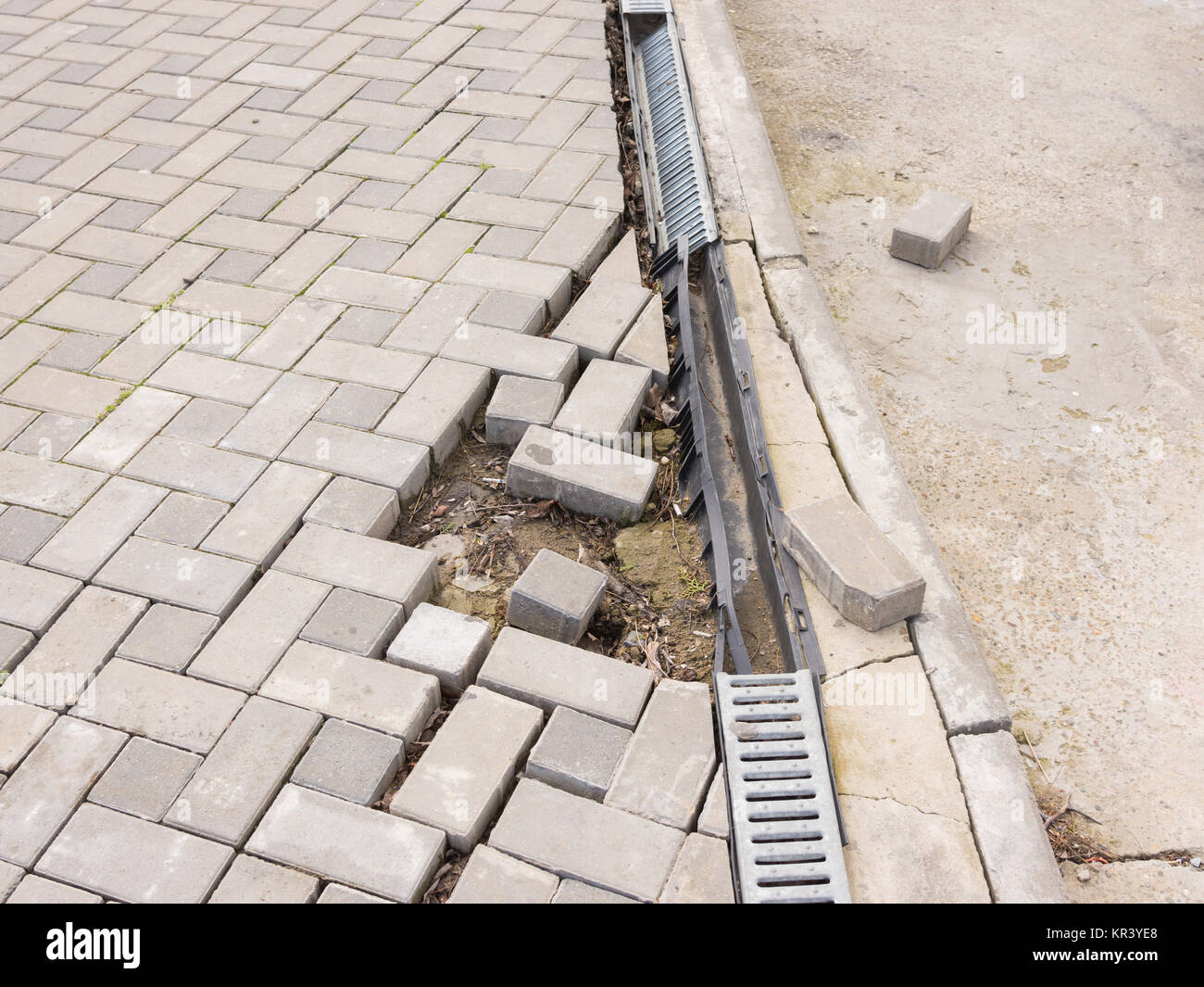 La distruzione del passaggio pedonale di pavimentazione con il drenaggio e la strada concreta Foto Stock