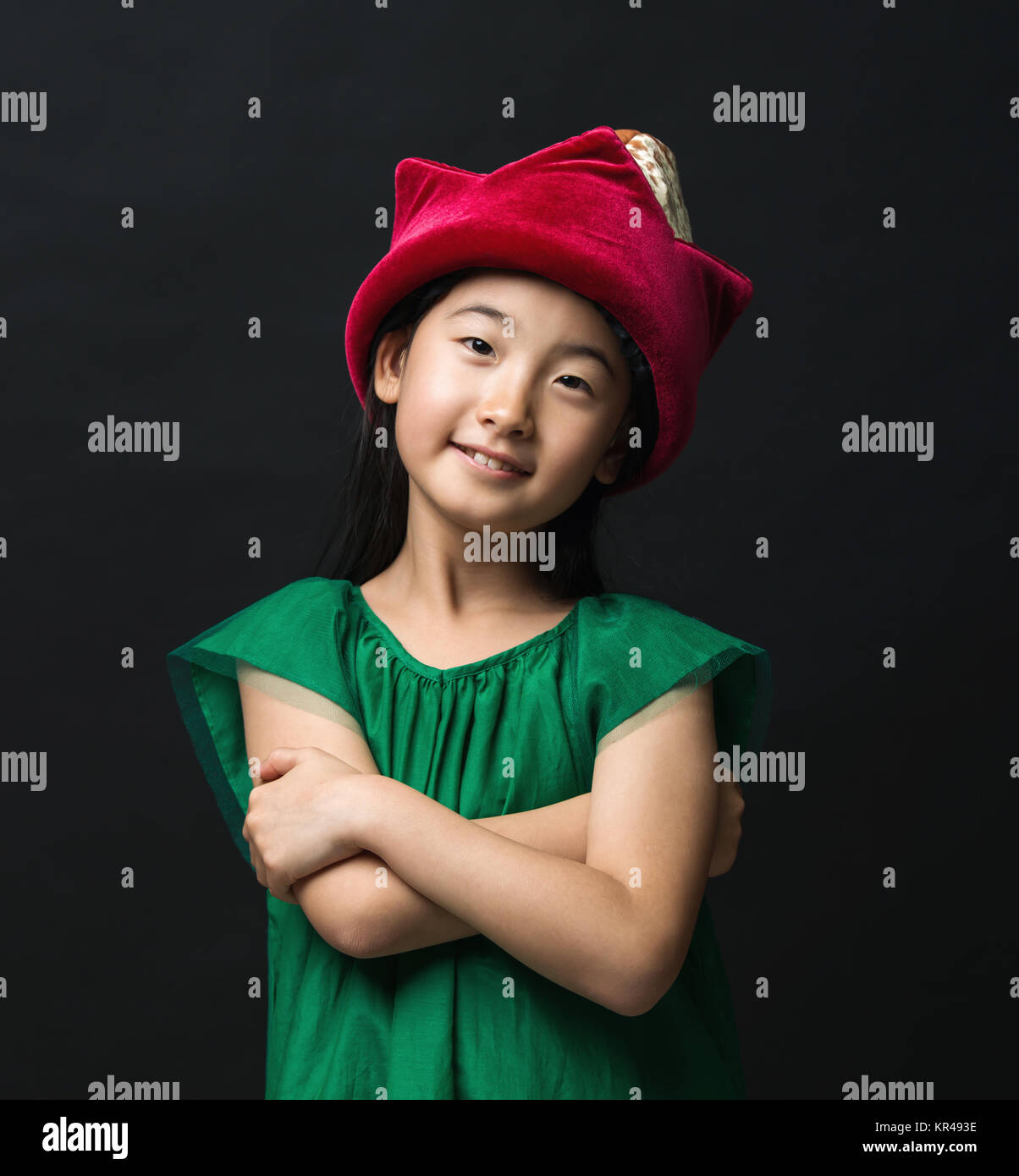 Carino ragazza asiatica bambino vestito in fairy hat e abito verde su uno sfondo nero. Foto Stock