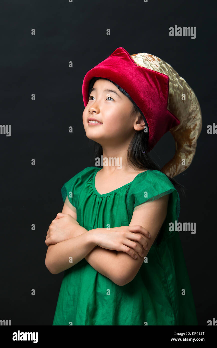 Carino ragazza asiatica bambino vestito in fairy hat e abito verde su uno sfondo nero. Foto Stock