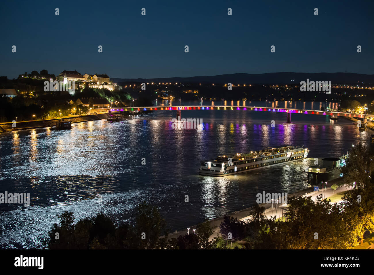 Petrovaradin Fortress e Rainbow ponte sul Danubio, tra Novi Sad e Petrovaradin al chiaro di luna con nave docking Foto Stock