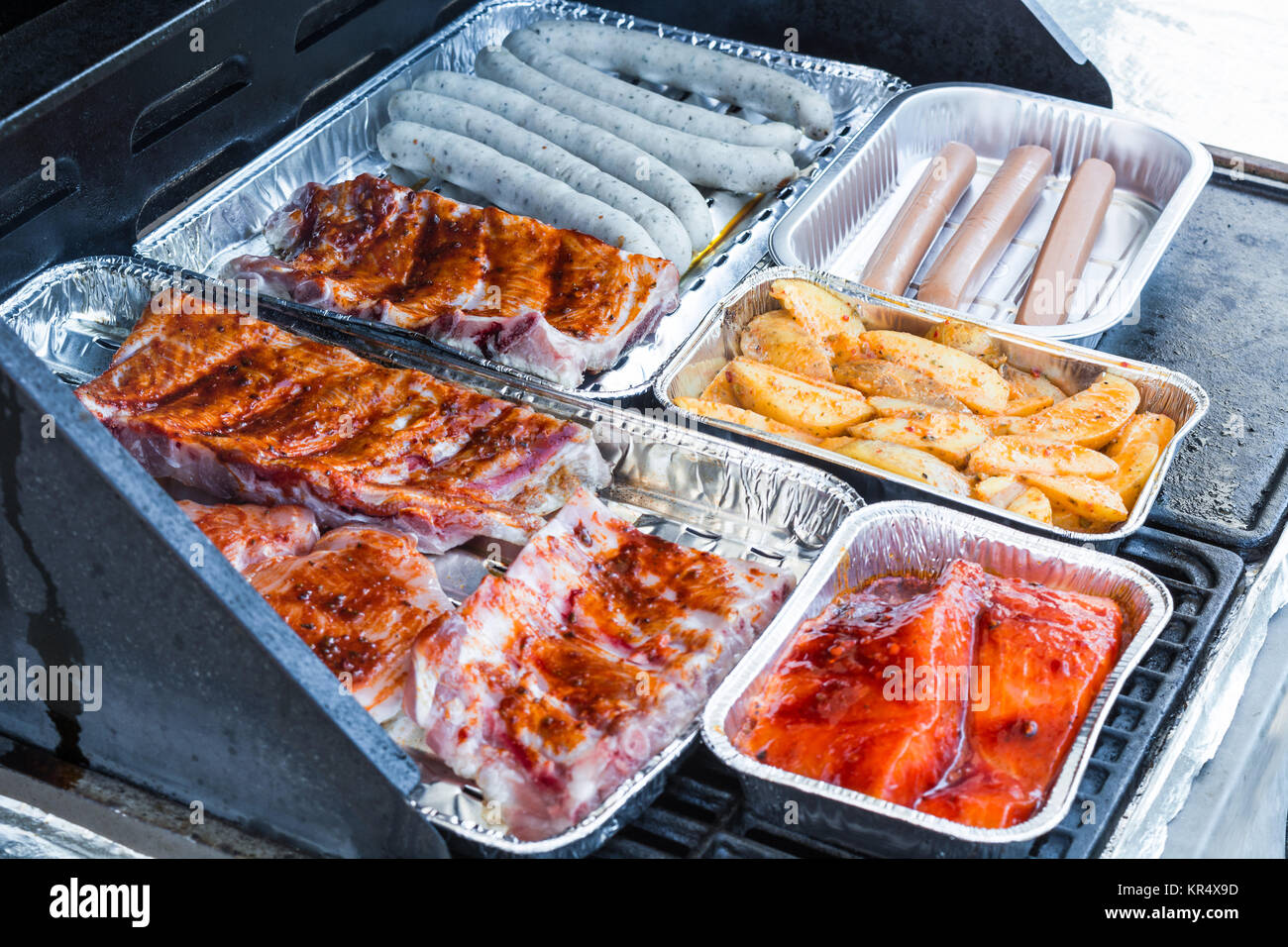 La carne e le salsicce alla griglia su un grill a gas. Foto Stock