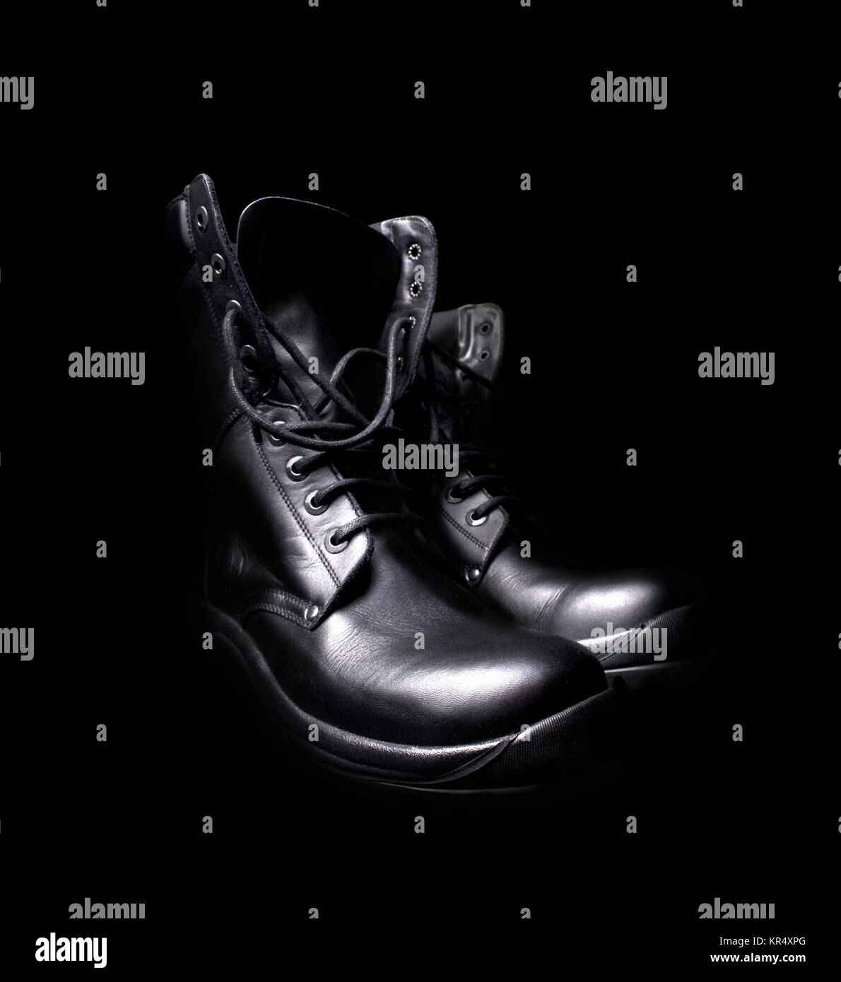 Una coppia di cuoio nero stivali militari su sfondo nero Foto Stock