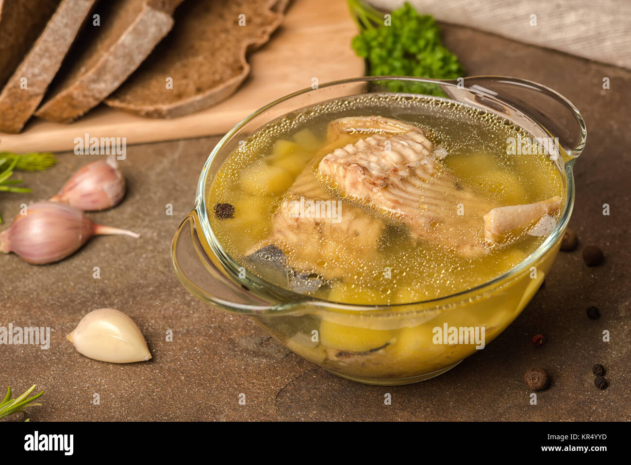 Zuppa di pesce con lo storione, patate in lastra trasparente, decorato di aglio, foglie di prezzemolo e tagliate il pane di segale, uno stile di vita sano Foto Stock