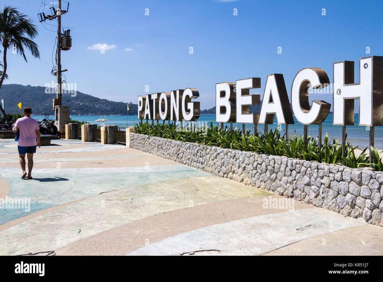Un uomo cammina davanti ad una spiaggia di Patong segno, Phuket, Tailandia Foto Stock