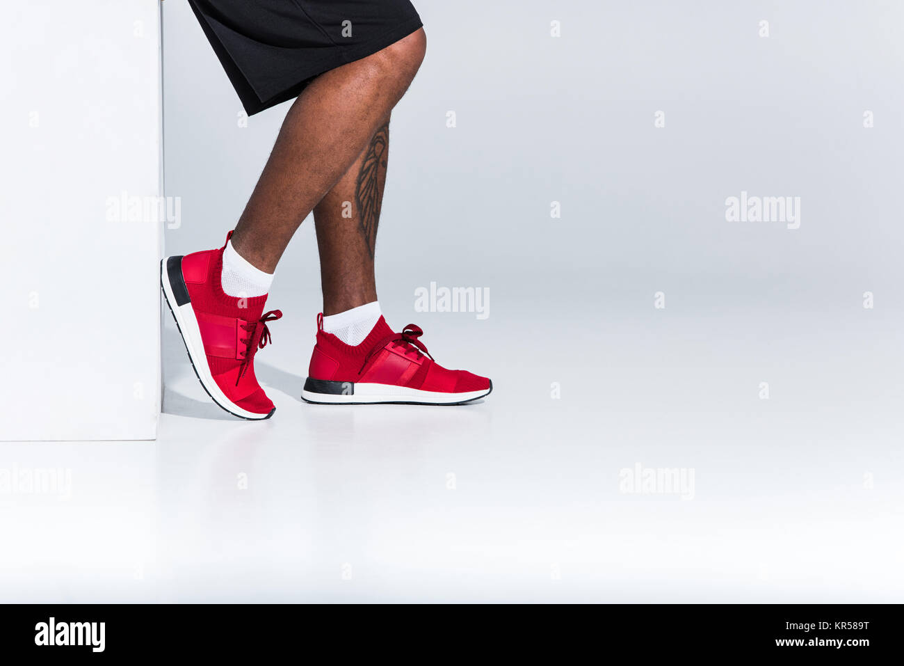 Ritagliato shot di giovani africani sportivo americano in rosso sneakers su grigio Foto Stock