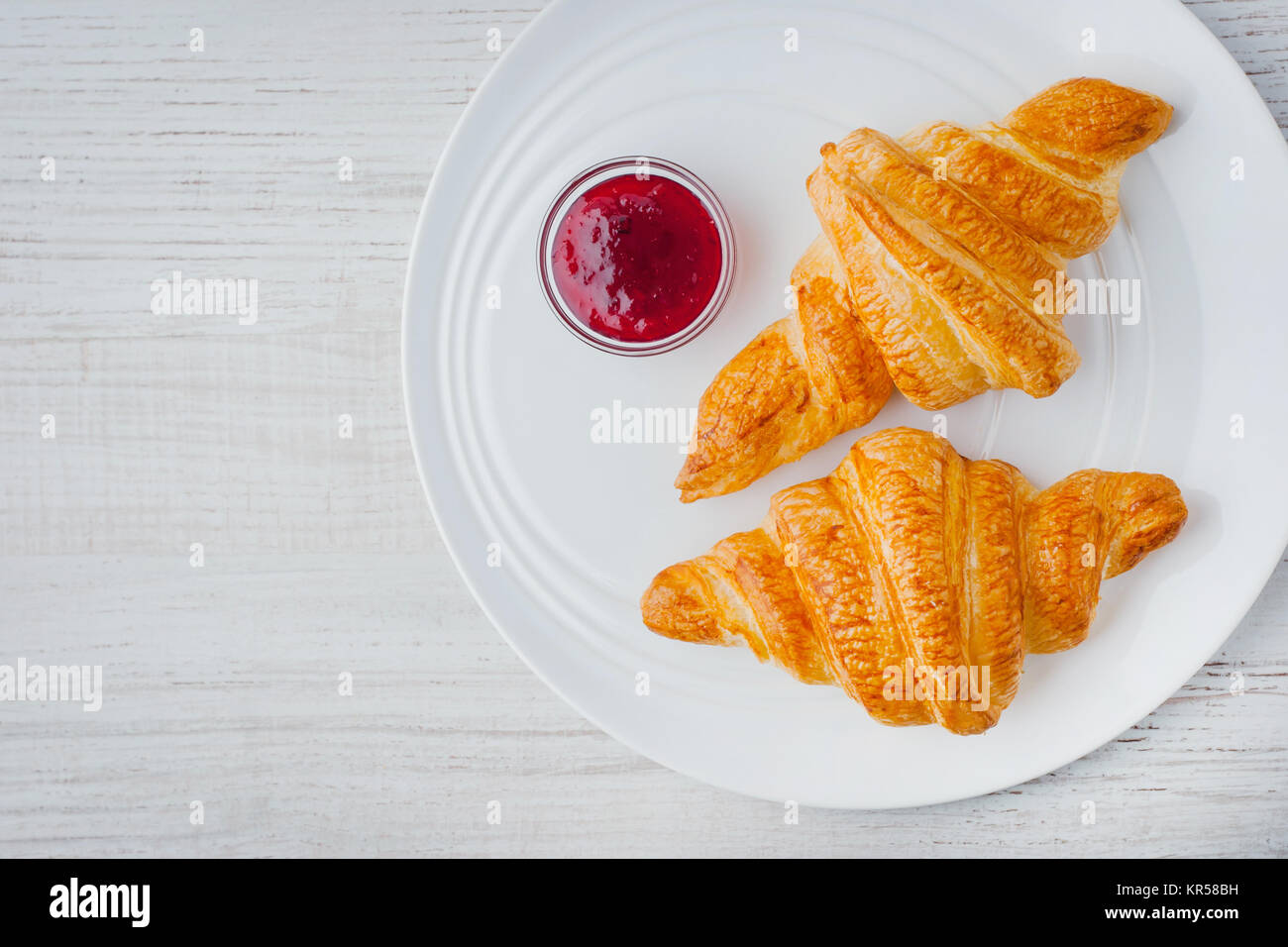 Due croissant con marmellata di frutti di bosco sul piatto di portata in ceramica bianca vista superiore Foto Stock