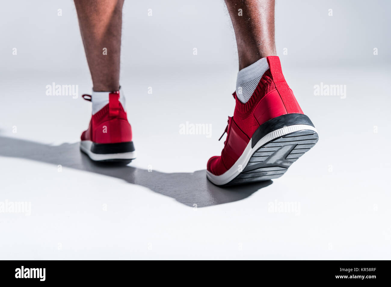 Vista parziale di African American uomo in calzature sportive su grigio Foto Stock