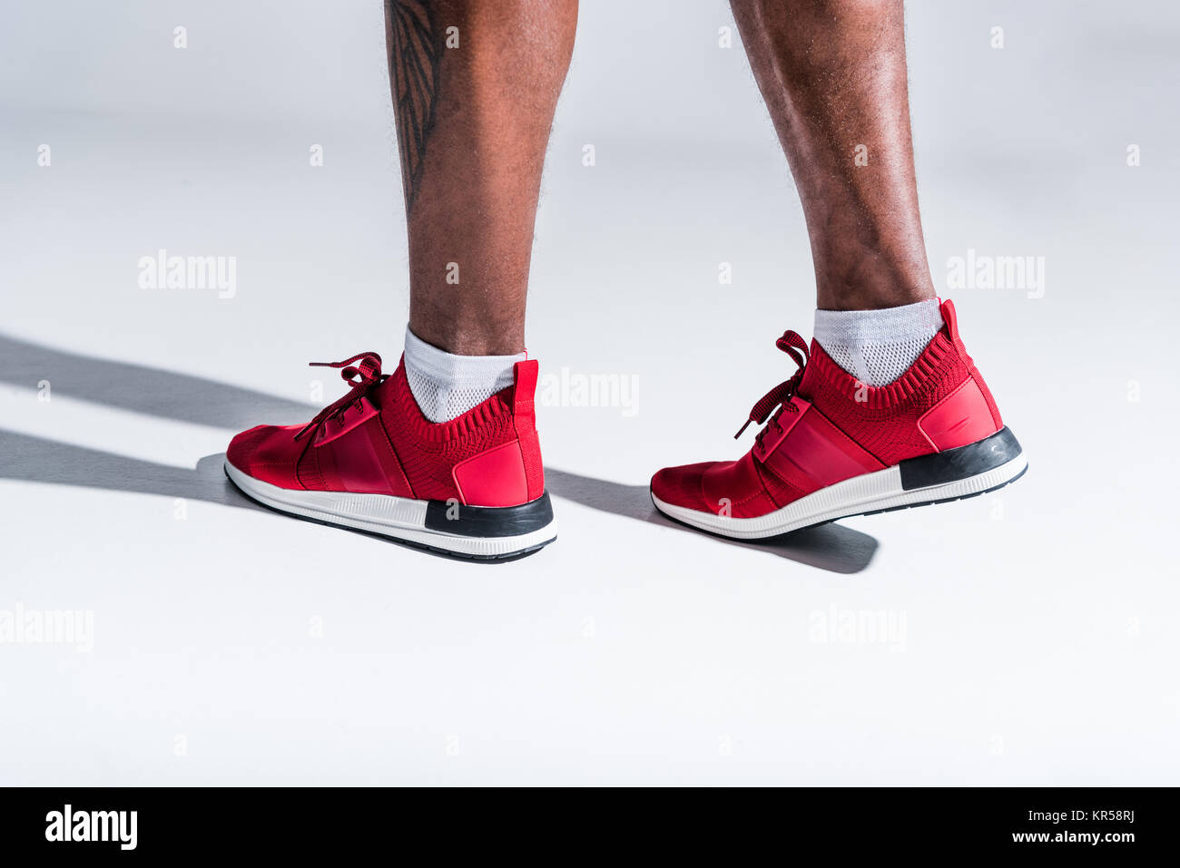 Ritagliato colpo di African American uomo in calzature sportive su grigio Foto Stock