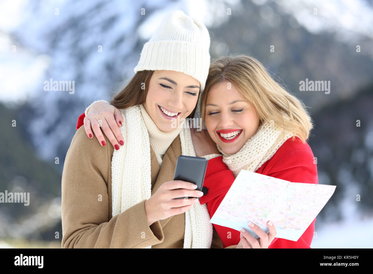 Due turisti felici ricerca posizione sulla linea in uno smart phone in vacanze invernali in una montagna innevata Foto Stock
