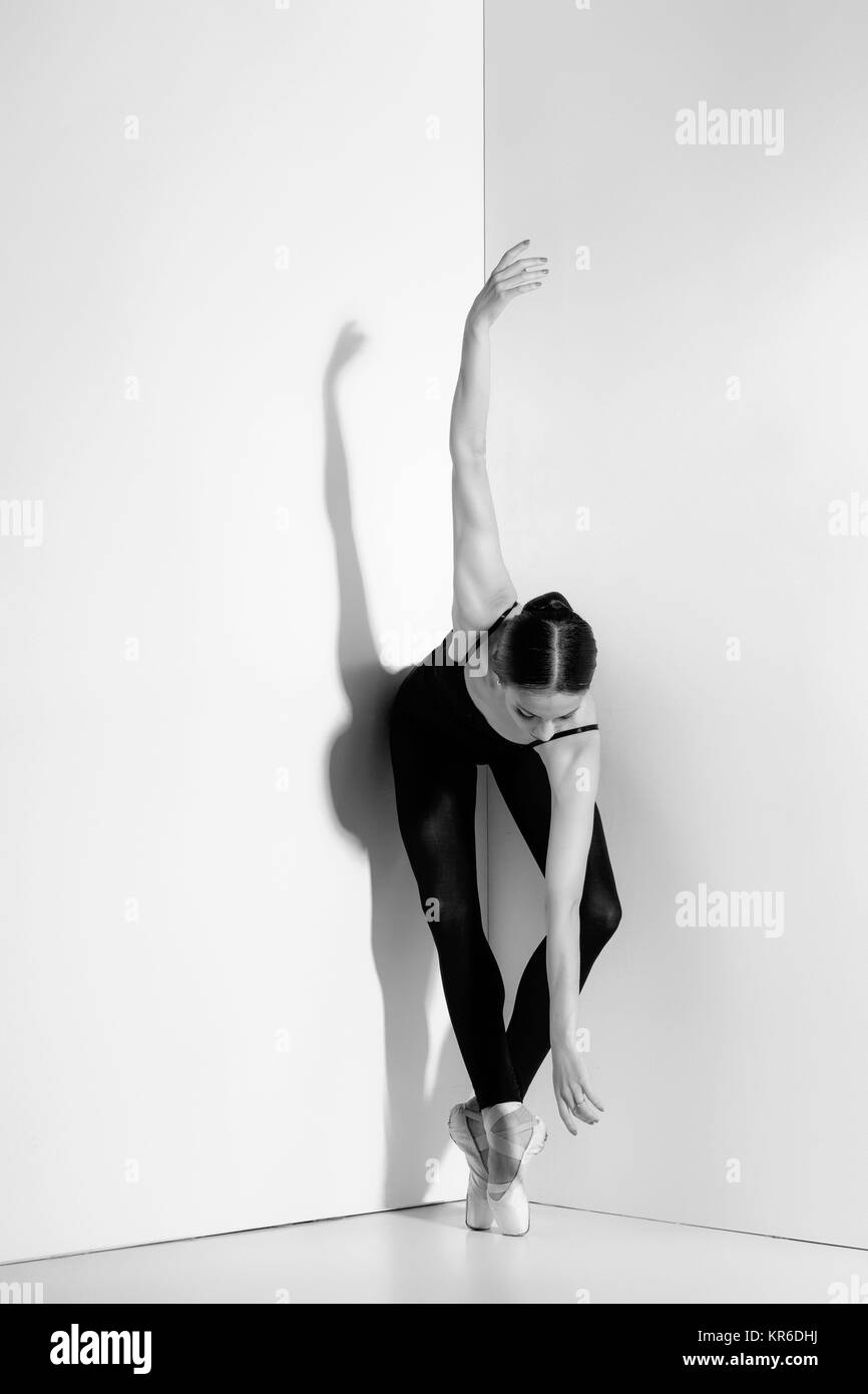 Ballerina in abito nero in posa sul pointe scarpe, di sfondo per studio. Foto Stock
