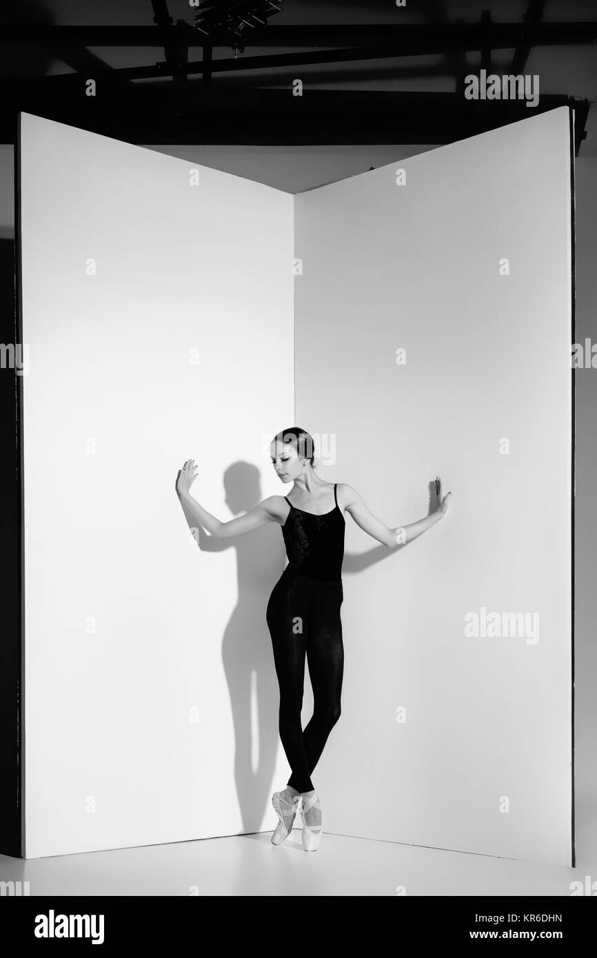 Ballerina in abito nero in posa sul pointe scarpe, di sfondo per studio. Foto Stock