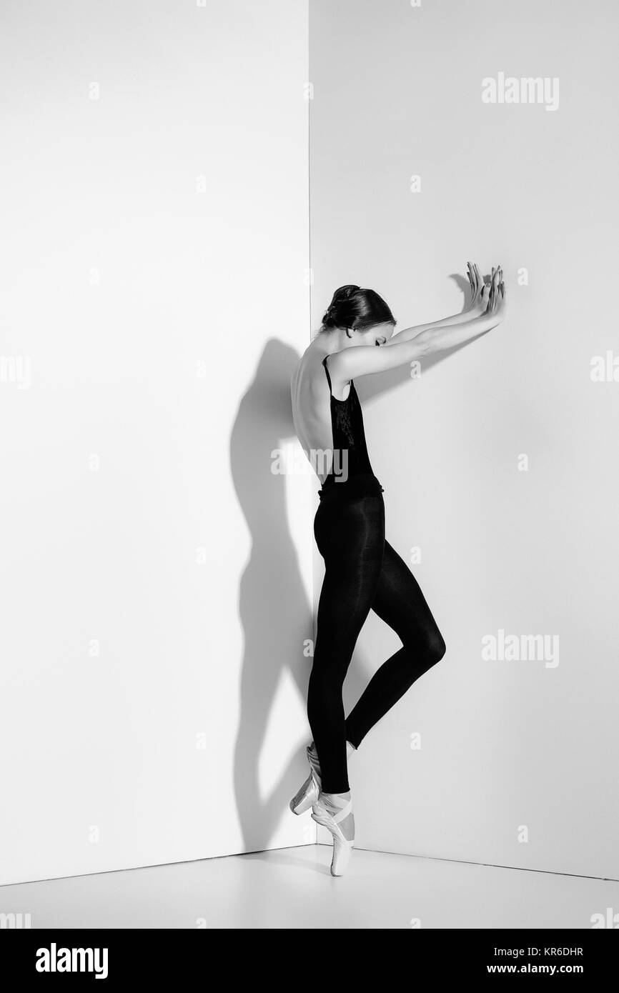 Ballerina in abito nero in posa sul pointe scarpe, di sfondo per studio. Foto Stock