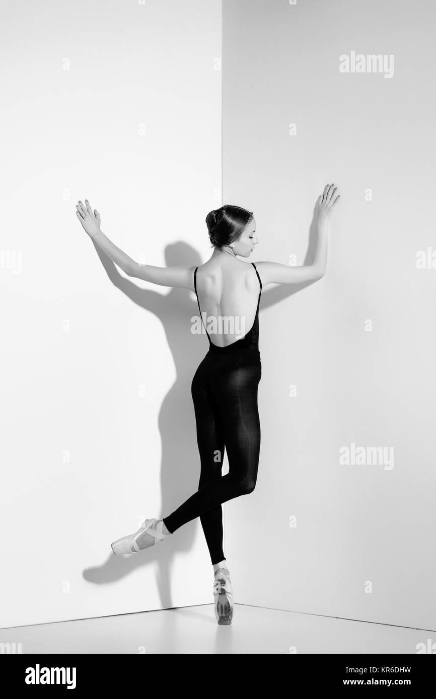 Ballerina in abito nero in posa sul pointe scarpe, di sfondo per studio. Foto Stock