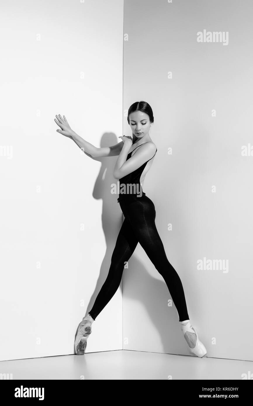 Ballerina in abito nero in posa sul pointe scarpe, di sfondo per studio. Foto Stock