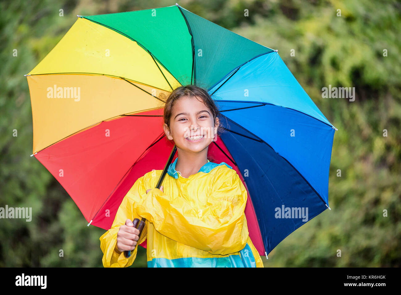 Felice bambina con colorati ombrello e impermeabile a giocare sotto la  pioggia Foto stock - Alamy