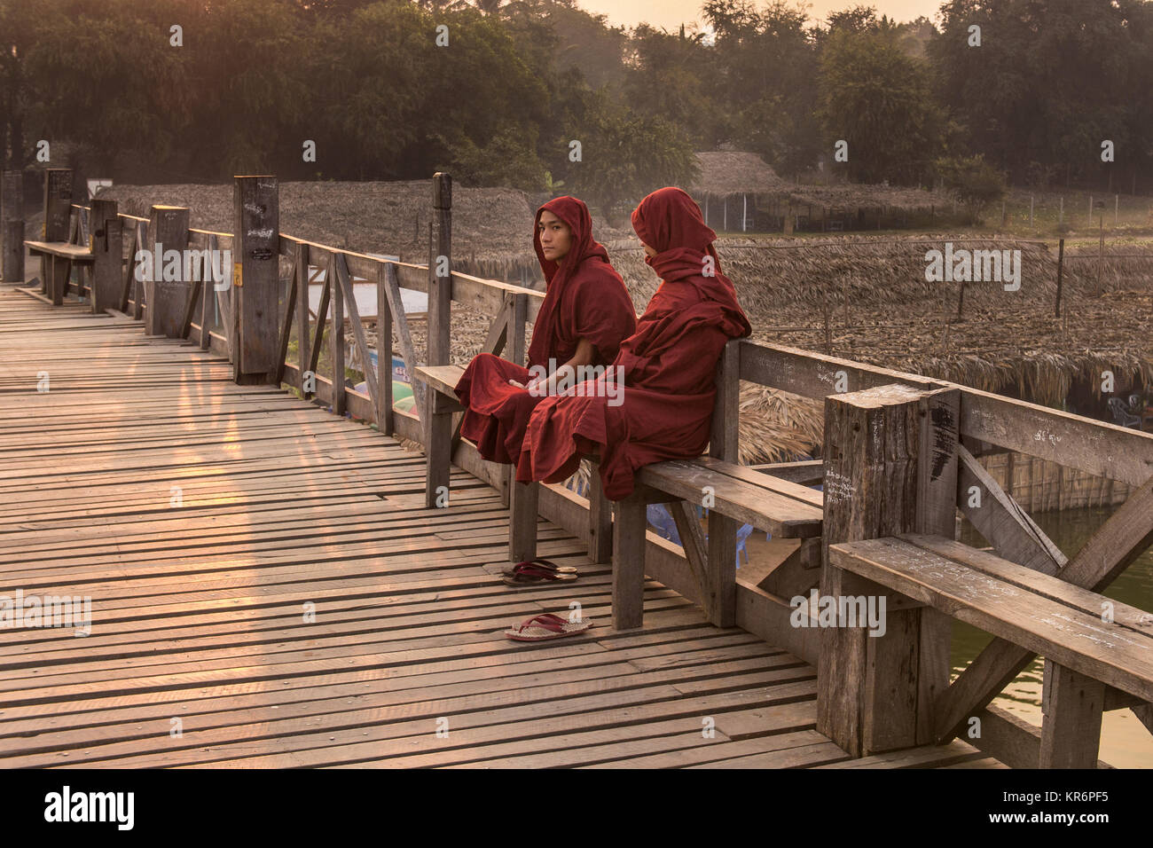 I monaci birmani di posti a sedere su una panca in legno, U Bein Bridge, Amarapura, Birmania, Febbraio 2012: due monaci birmani seduta su una panca in legno a sunrise. Foto Stock