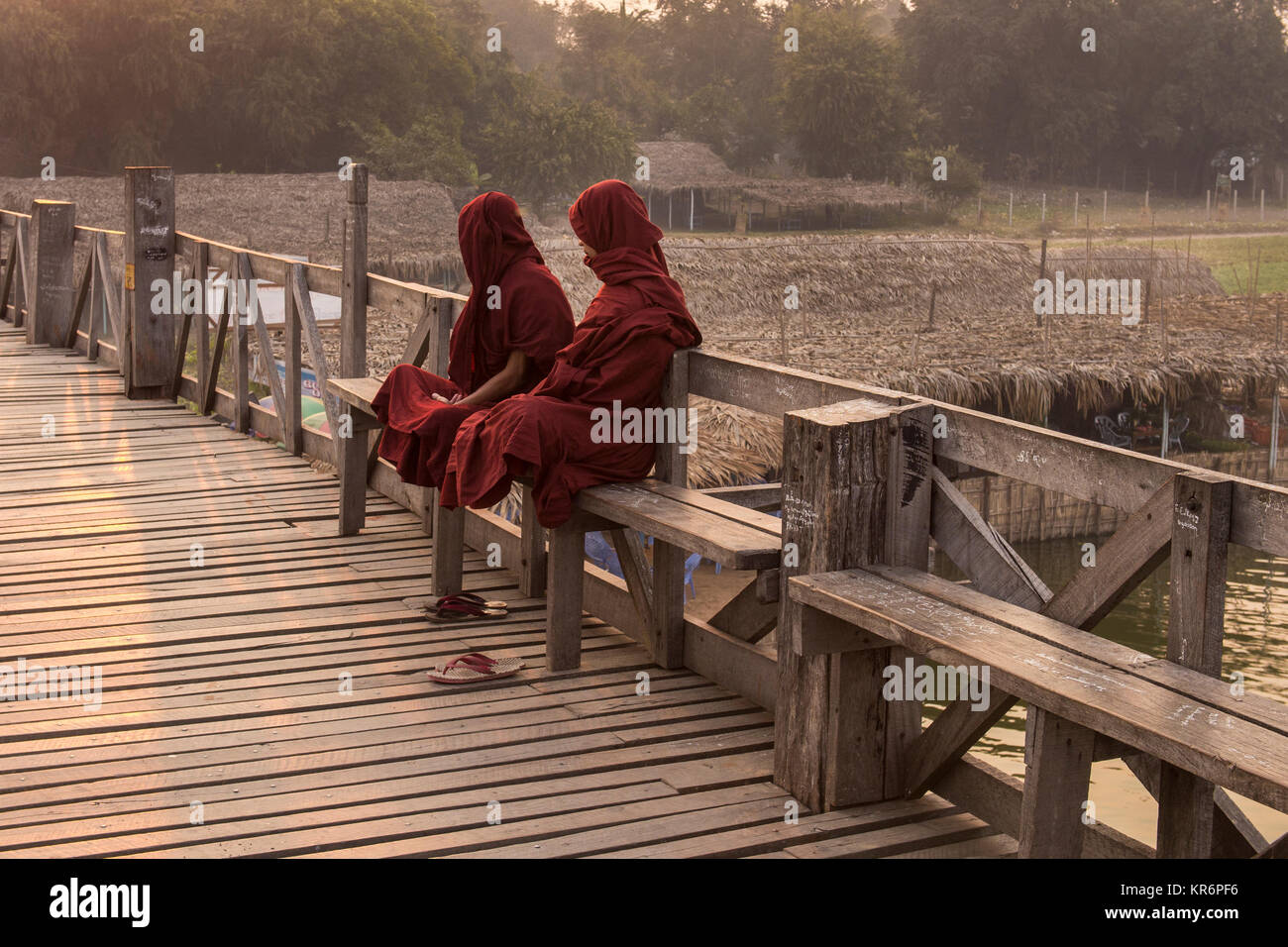 I monaci birmani di posti a sedere su una panca in legno, U Bein Bridge, Amarapura, Birmania, Febbraio 2012: due monaci birmani seduta su una panca in legno a sunrise. Foto Stock