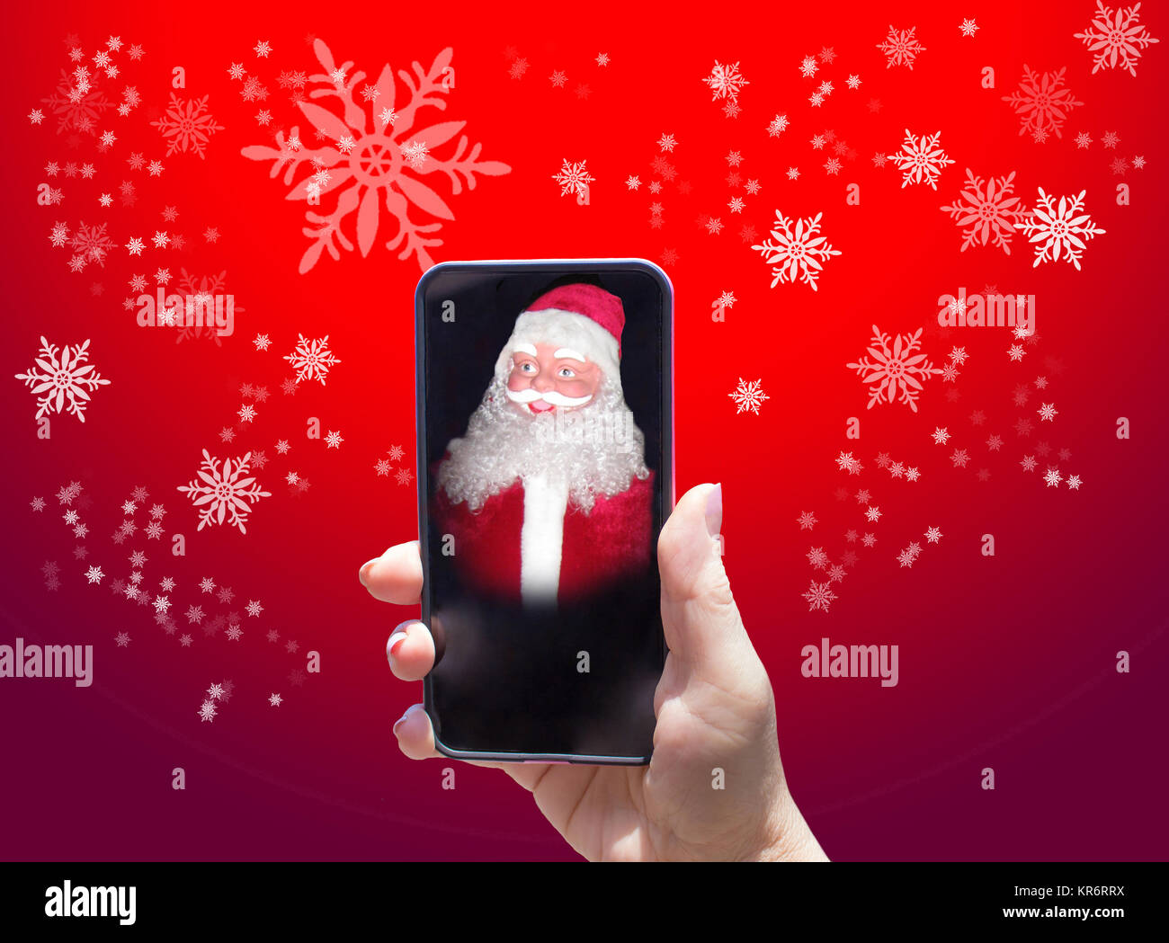 La mano femminile e il telefono con Babbo Natale su sfondo rosso Foto Stock