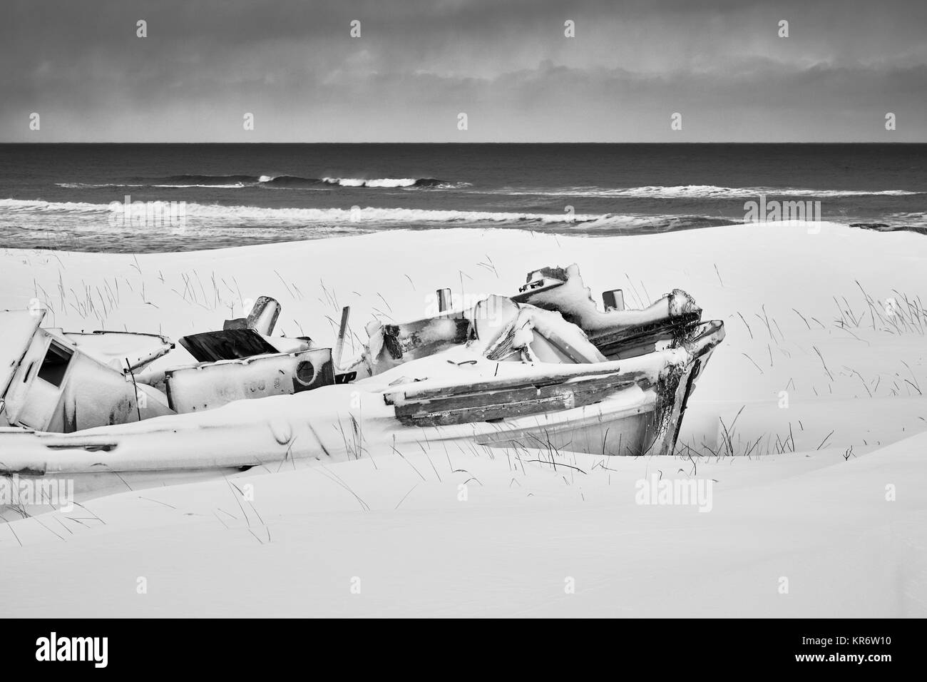 Barca da pesca che giace sulle dune coperte di neve e ghiaccio in inverno. Foto Stock