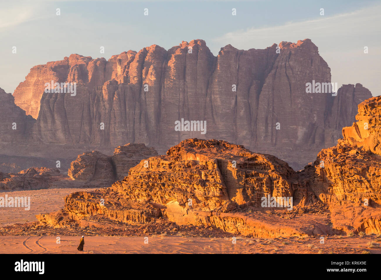 Beduino a piedi attraverso il paesaggio del deserto con rocce e montagne. Foto Stock
