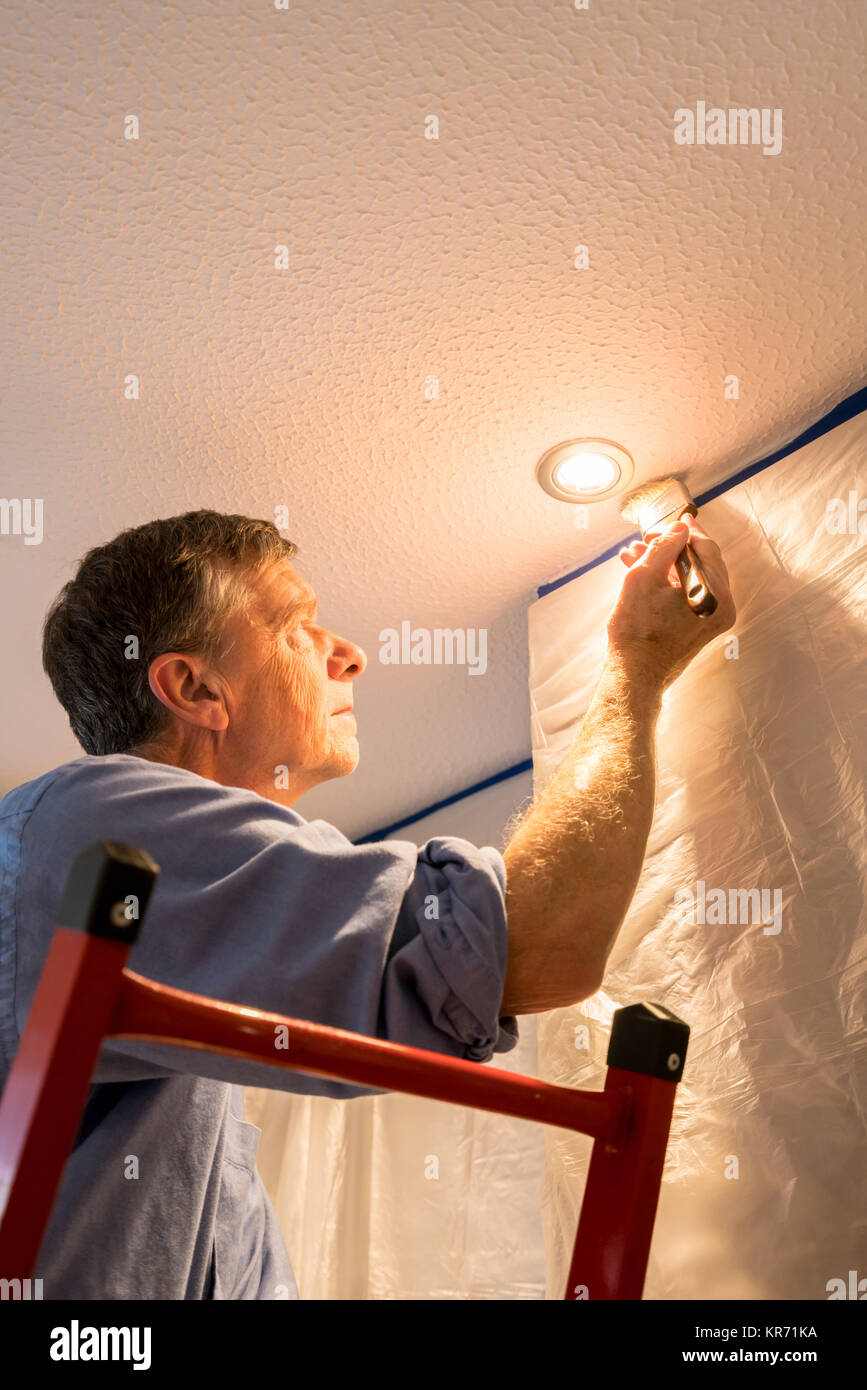 Senior adulto uomo pittura soffitto della cucina Foto Stock