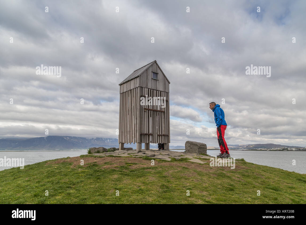 Nella parte superiore della Thufa, un uomo tumulo verde nel lungomare di Reykjavik, Islanda, con una piccola casa in legno utilizzato per essiccare il pesce Foto Stock