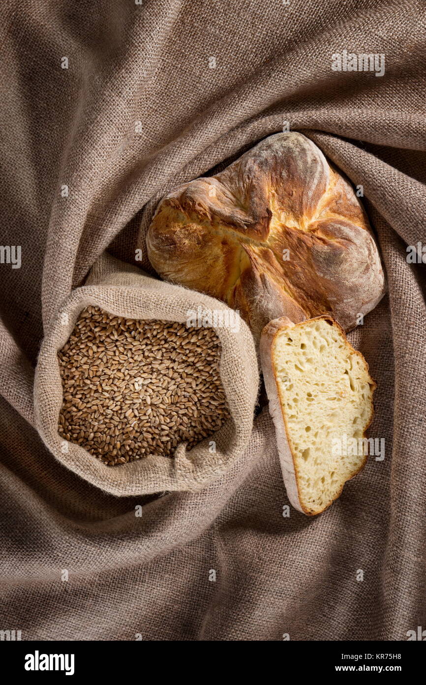 Pane e un sacco di grani posto su un cilicio Foto Stock