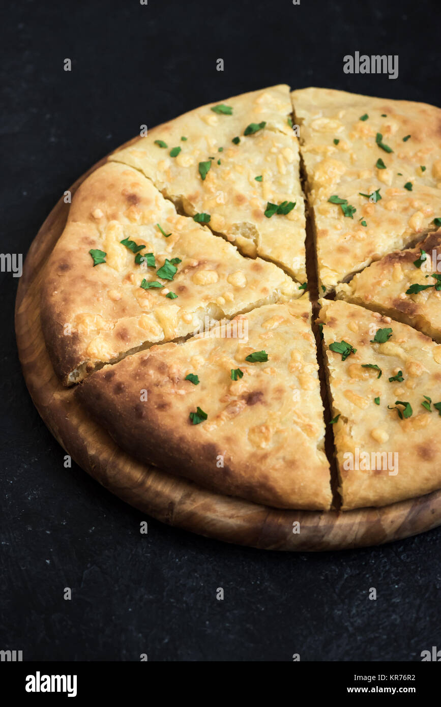 Tradizionale georgiano flatbread - khachapuri o hachapuri con doppio formaggio. Imereti khachapuri nero sul tavolo di pietra con copia spazio. Foto Stock