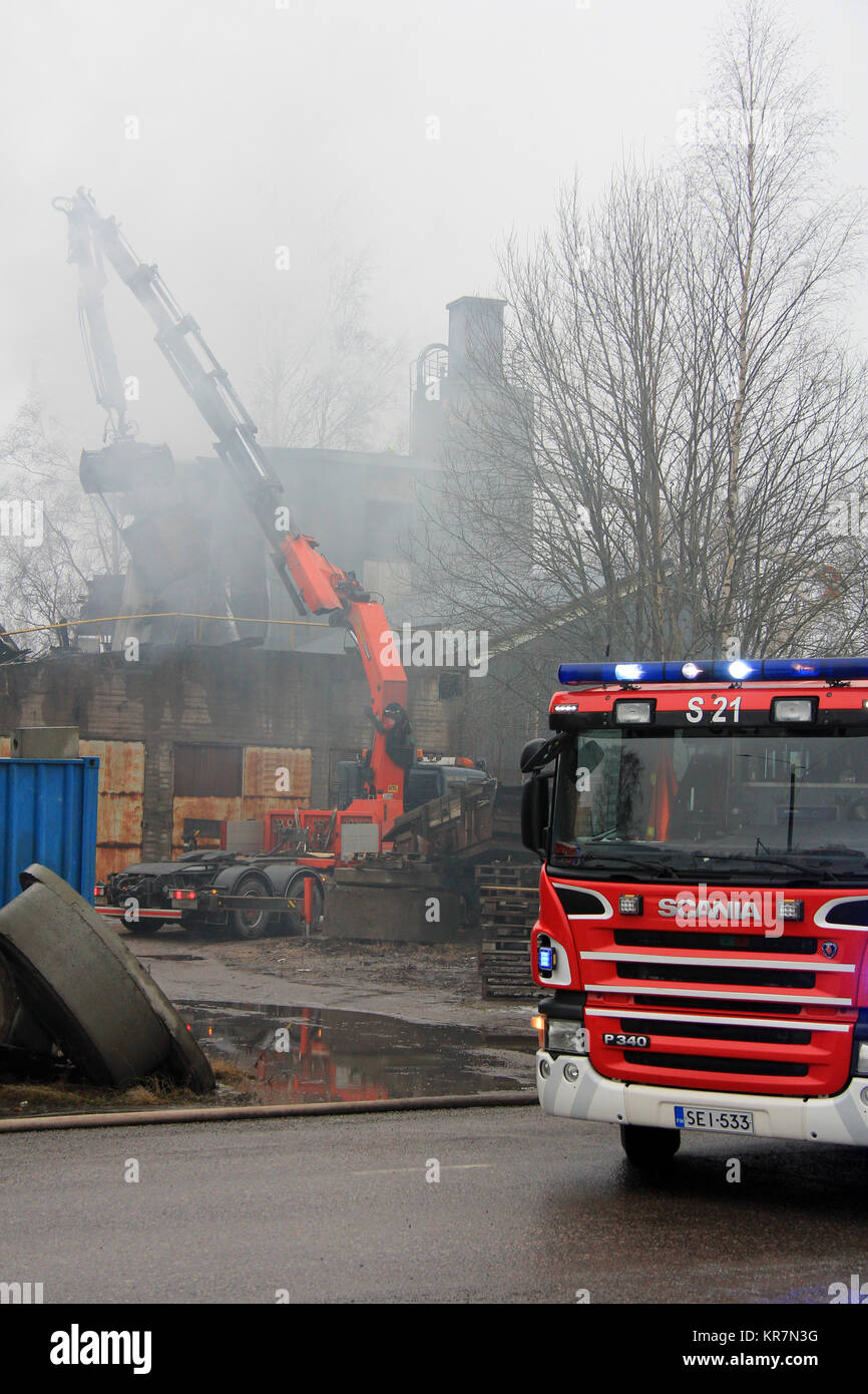 SALO, Finlandia - 16 febbraio 2014: Firefightes estinguere il fuoco sotto le ceneri a Salo impianto di cemento con l aiuto di una gru mobile. Foto Stock